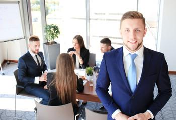 Young businessman standing in office with his collegue on the background