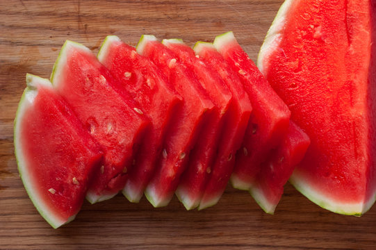 A few cloves of chopped juicy watermelon on a wooden tray.