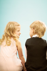 Rear view of two cute blond hair children sitting together