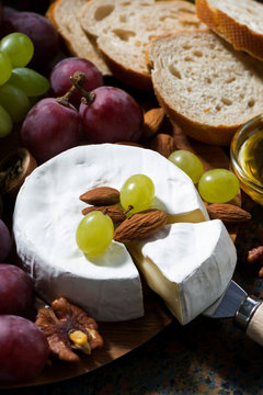 Camembert cheese, fruits and honey on dark background, vertical