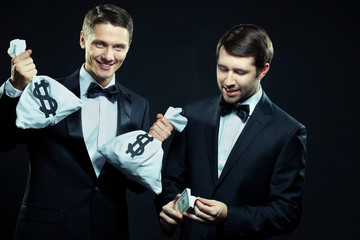 Two smiling men counting dollars isolated on black