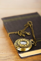 Pocket watch and book against a rustic background