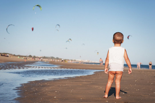 Naked baby in sleeveless shirt on beach