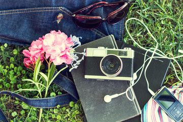 Libro, música, cámara de fotos y bolso sobre césped natural al aire libre. Vista superior