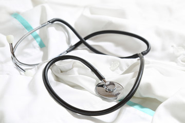 Stethoscope lies over white medical gown - healthcare and medicine concept. Close up photo