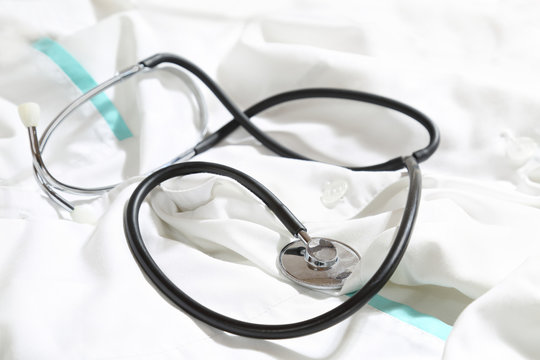 Stethoscope lies over white medical gown - healthcare and medicine concept. Close up photo