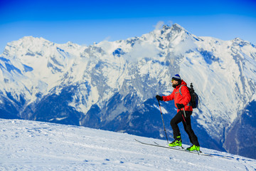 Fototapeta na wymiar Ski touring man reaching the top at sunrise in Swiss Alps.