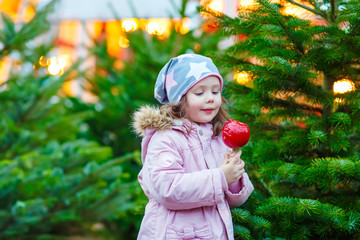 cute little girl eating sugar apple on Christmas market