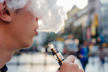 man using vape or electronic cigarette against the background of