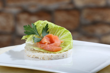 Sharply focused close up of fresh salmon canape on blurred stone wall background. Image for a restaurant snack menu or party invitation cover design