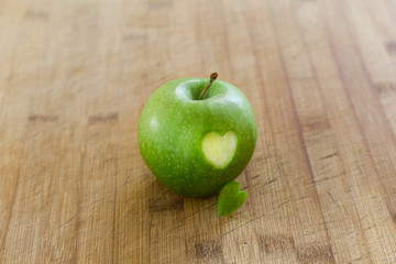 Manzana en mesa de madera con un corazon (concepto de dieta y salud) 