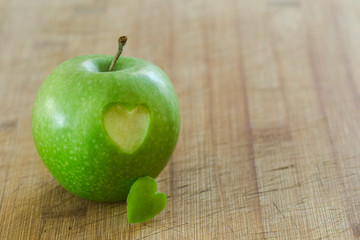 Manzana en mesa de madera con un corazon (concepto de dieta y salud)