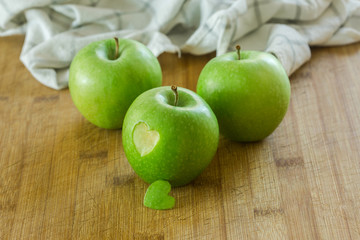 Tres manzanas en una mesa de madera con un corazon (concepto de dieta y salud) 