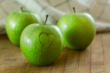 Manzana en mesa de madera con un corazon (concepto de dieta y salud)