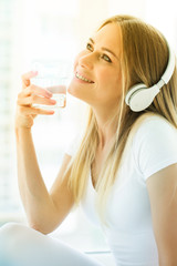 Close-up portrait. Young woman drinking a glass of water at home