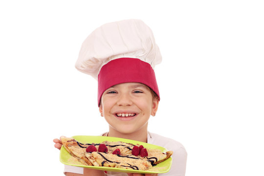 happy little girl cook with crepes on plate