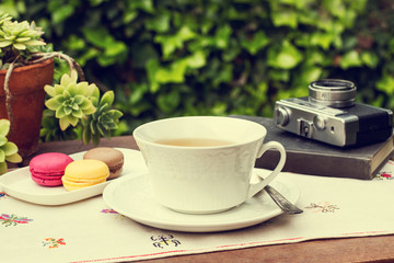 Taza de té con macarons libro y cámara de fotos al aire libre
