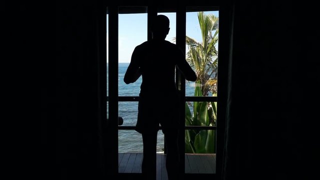 Silhouette of man opening door and walking out on terrace, super slow motion 240fps 
