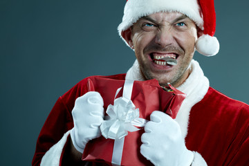 Portrait of crazy Santa Claus chewing a gift box