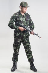 Asian soldier in green camouflage uniform with long gun