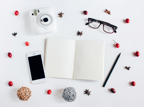 Creative flat lay of blank notebook, smartphone, instant camera