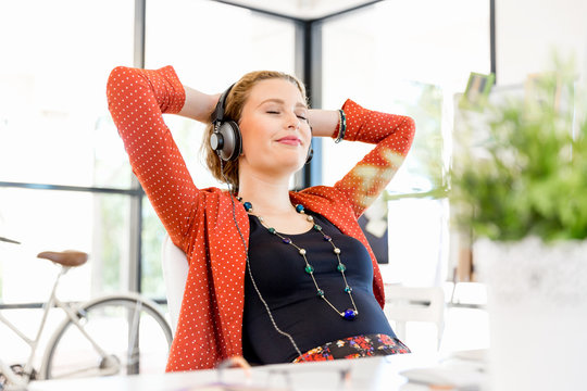 Young woman in office with headphones