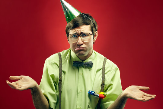 Portrait of sad nerd in party hat at a loss