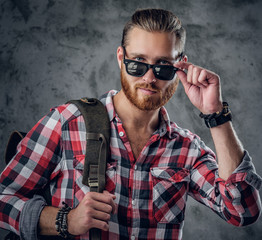 Redhead urban traveller male holds backpack.