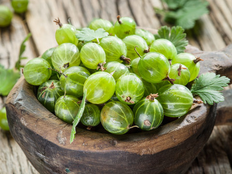 Gooseberries in the wooden bowl on the table.