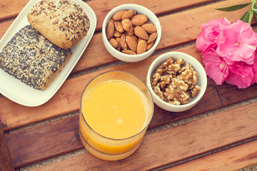 Bandeja de madera con Vaso de zumo de naranja y frutos secos y pan al aire libre. Vista superior