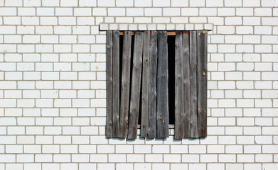 Boarded up window in a white brick wall