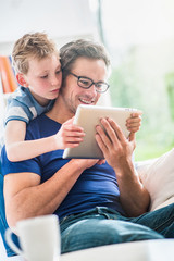 At home, a father and his young son sharing a video on a tablet