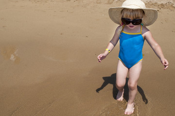 Cute happy baby girl wearing swimming suit, sun glasses, hat