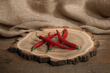 Red hot chili peppers on wooden canvas backround on rounded wooden plate
