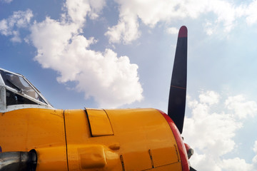 Propeller of old airplane against blue sky with clouds.