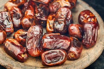 Dried dates fruit in rustic plate on black background