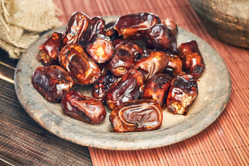 Dried dates fruit in rustic plate on wooden background