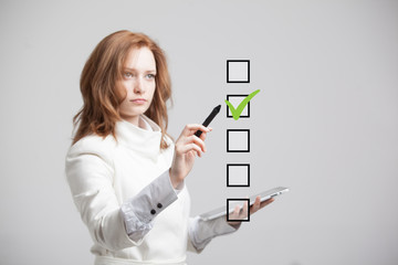 Young business woman checking on checklist box. Gray background.