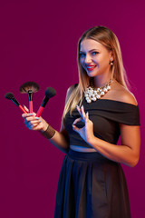 Woman makeup artist standing with brushes