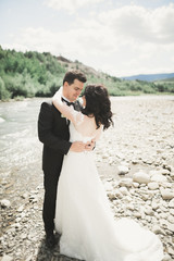 Fototapeta na wymiar Bride and groom holding beautiful wedding bouquet. Posing near river