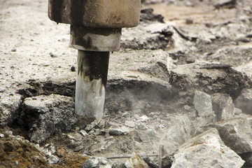 Excavator breaking and drilling the concrete road for repairing