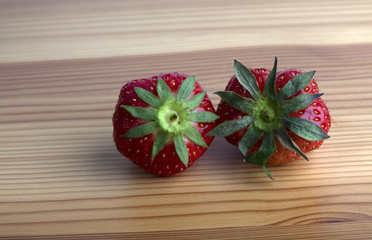 Two strawberries on a wooden shelf