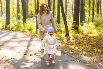 mother and daughter playing together in the autumn park