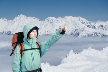 The mountaineer pointing at peak, standing against a winter mountain landscape.