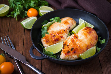 Chicken breasts with lime and parsley on dark wooden background close up. Healthy food. Nutritious meal.