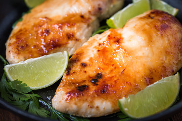Chicken breasts with lime and parsley on dark wooden background close up. Healthy food. Nutritious meal.
