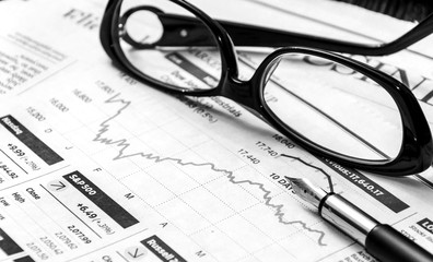 Pen with glasses on the business newspaper.