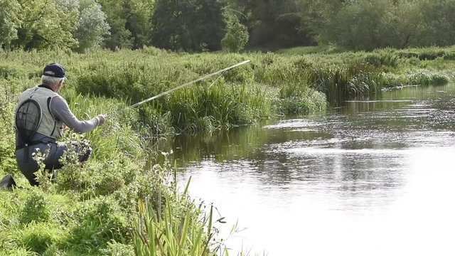 Flyfisherman fishing from riverbank, Irish countryside