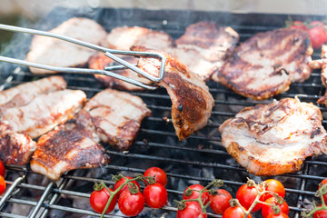 Pork steaks on the grill with flames and smoke
