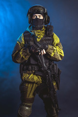 Fototapeta premium The man in the image of a member of the special forces division with assault rifle in blue light. Russian police special force - Special Rapid Response Unit or SOBR (Spetsnaz).